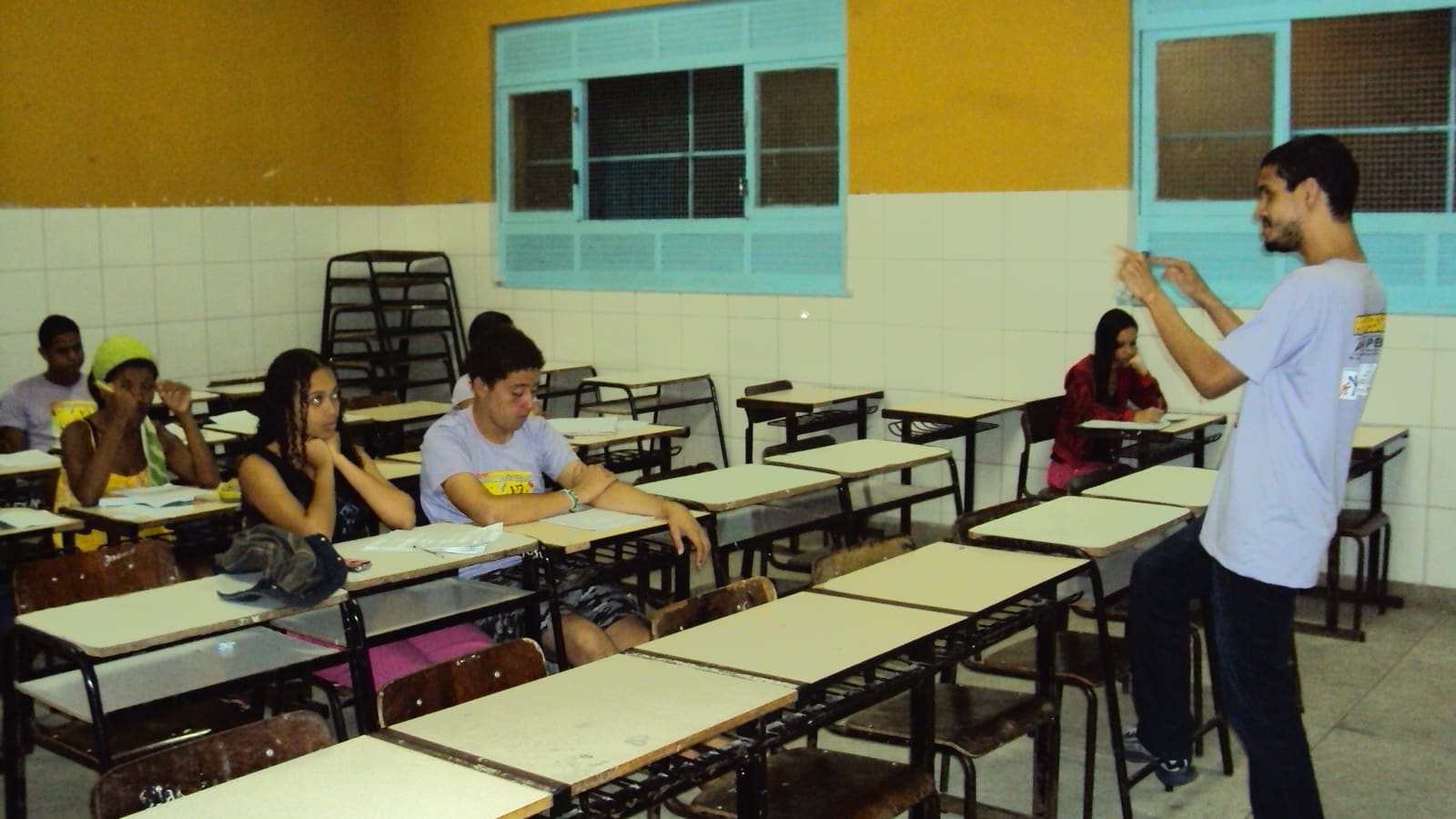 Professor jovem de pé dando aula para estudantes em uma sala de escola